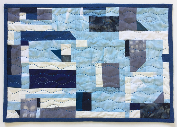 small randomly pieced quilt with wavy embroidered quilting and embroidered outlines of eyes