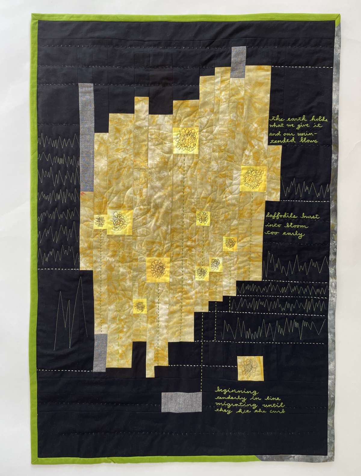 abstract pieced quilt with strips and stitched flowers and embroidered poem on a black background