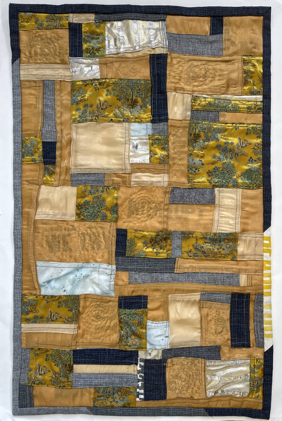 shimmery gold quilt made up of pieced rectangles with some quilted flowers