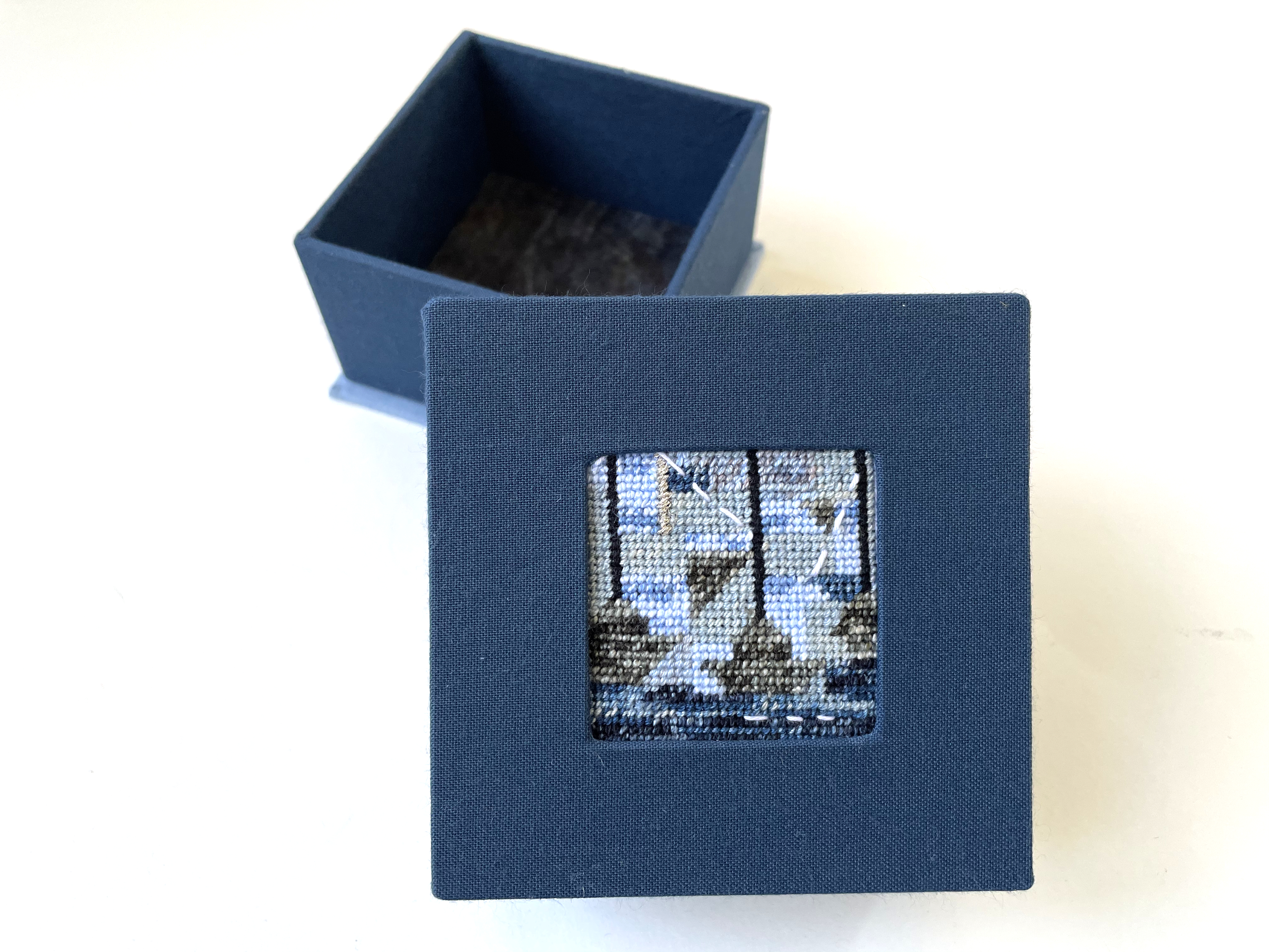 a box with an inset needlepoint of a boats and ocean