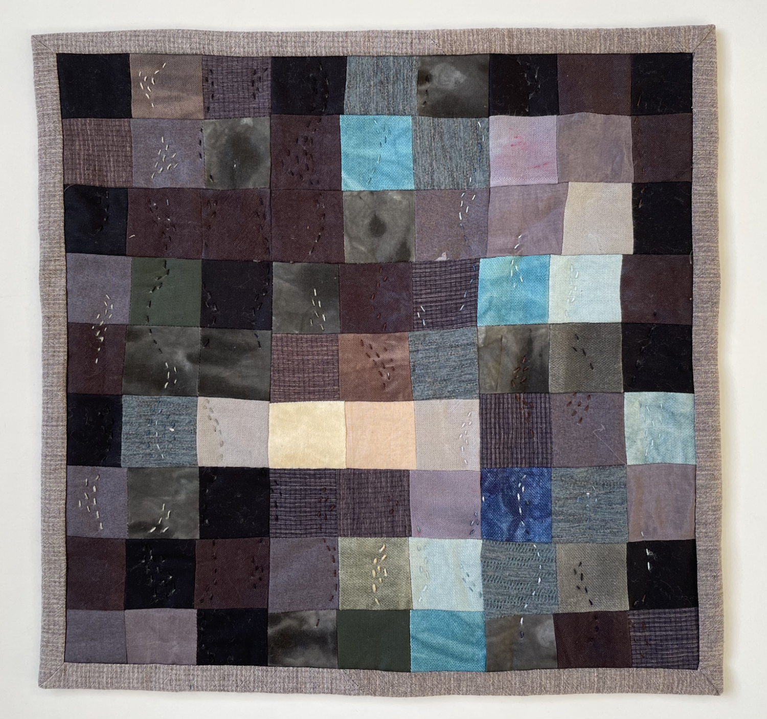 abstract pieced quilt with 9 x 9 squares in pond colors with four light squares in the upper one third