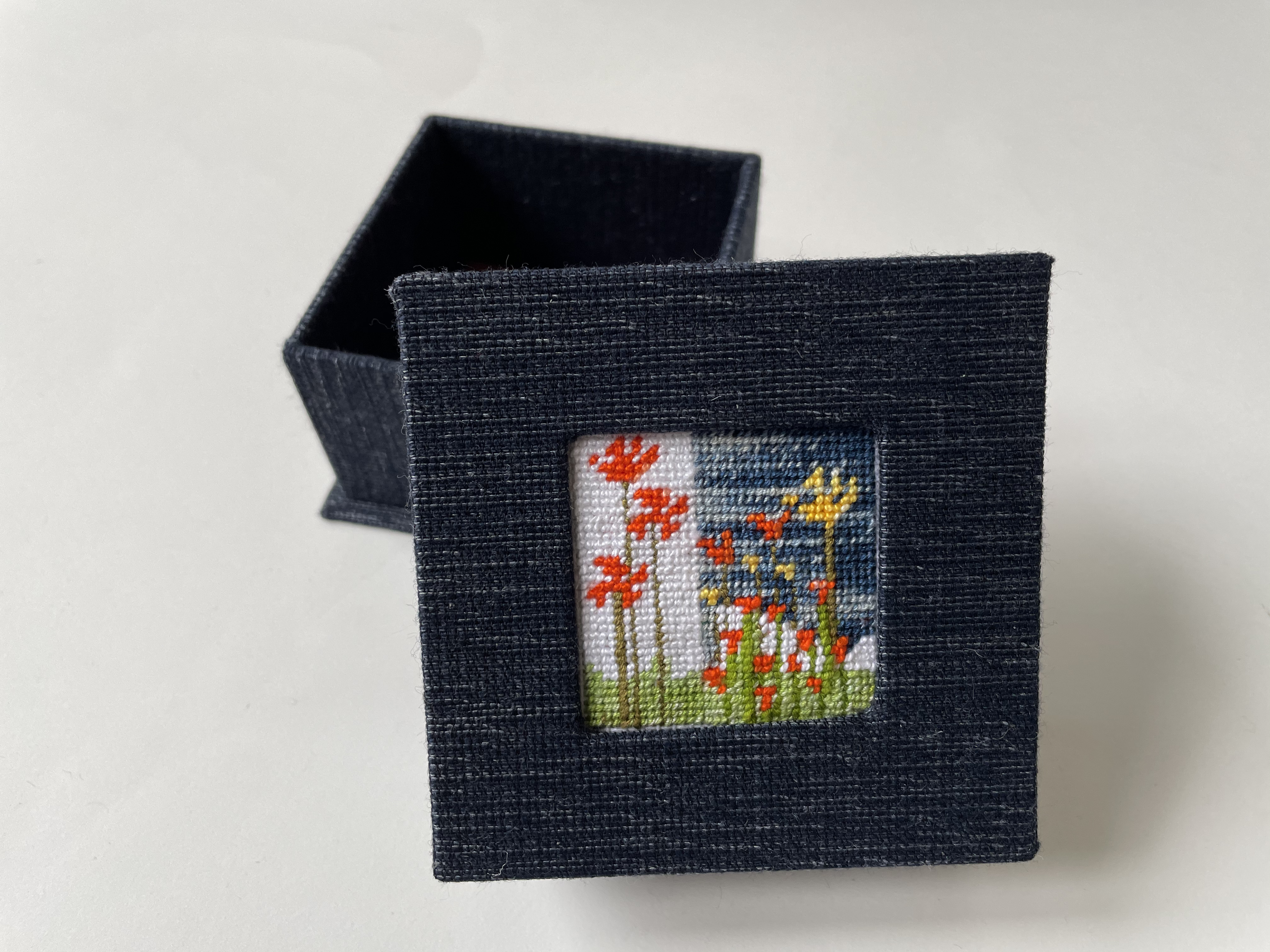 a box with an inset abstract needlepoint with California poppies