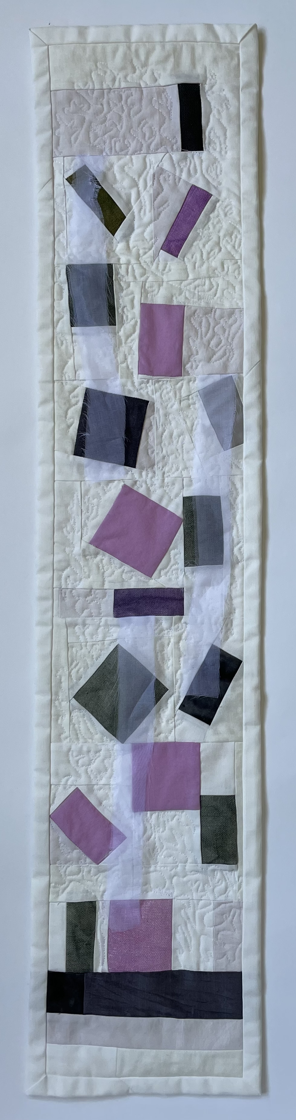 long narrow quilt with abstract shapes and three silk organza streamers sewn in