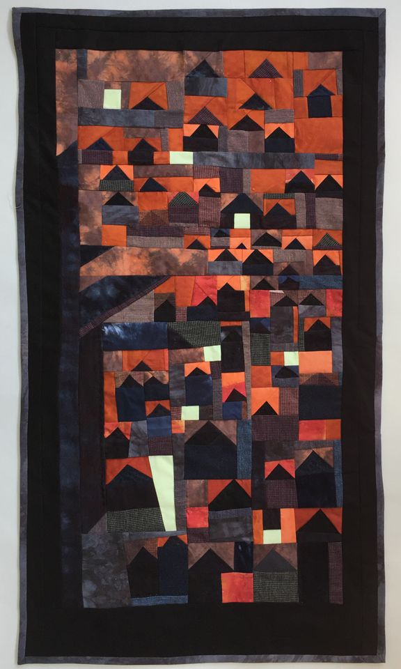 vertically oriented pieced quilt with many small house shapes and large tree