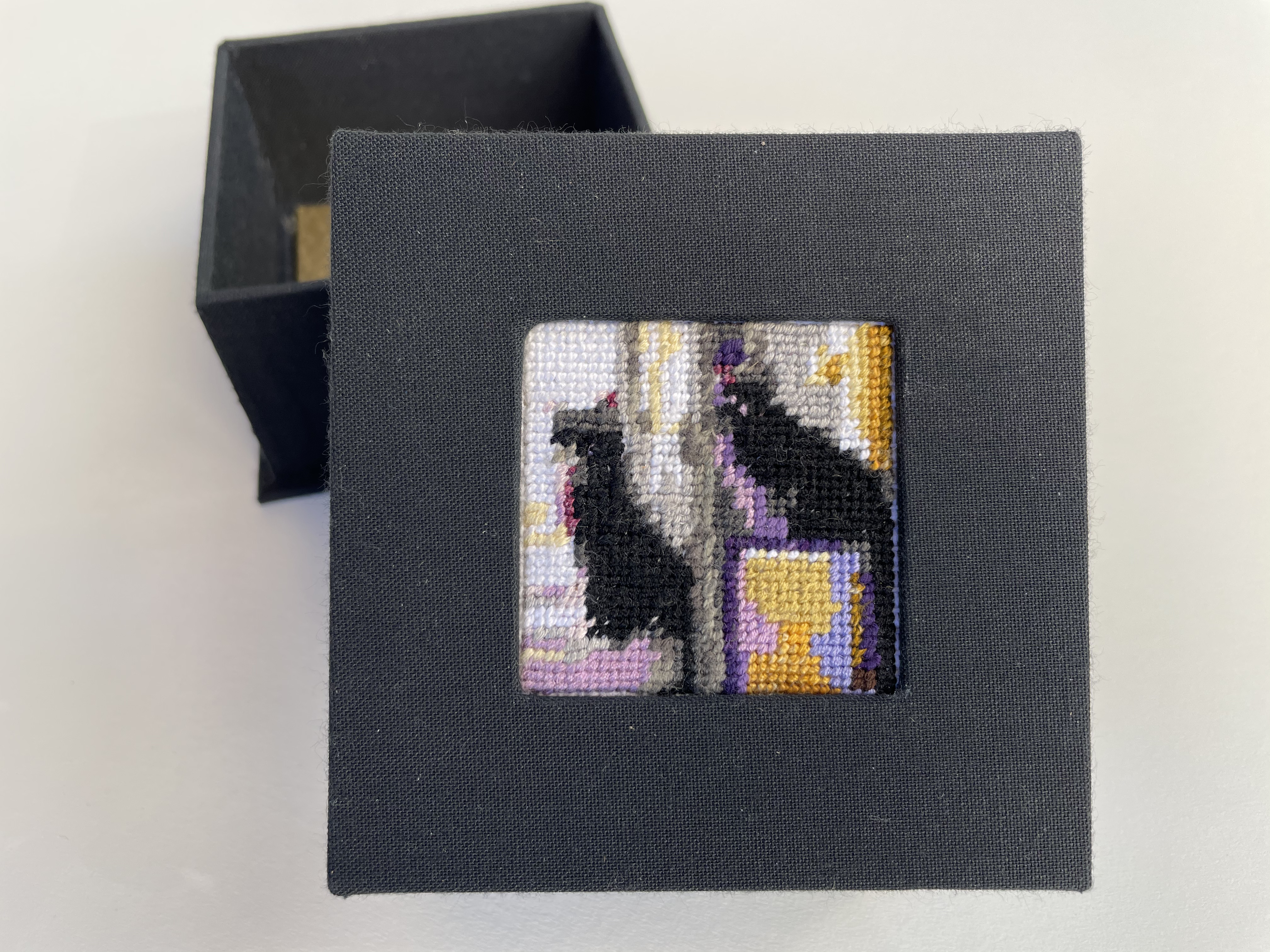 a box with an inset needlepoint of two cats by a window