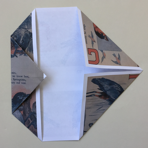 left point folded over and one half inch over the folded corners on left