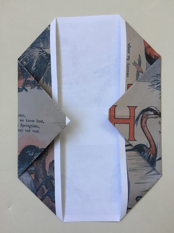 right point folded over and one half inch over the folded corners on right with left point still folded