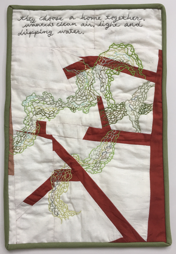 quilt with embroidered lace lichen hanging from tree
