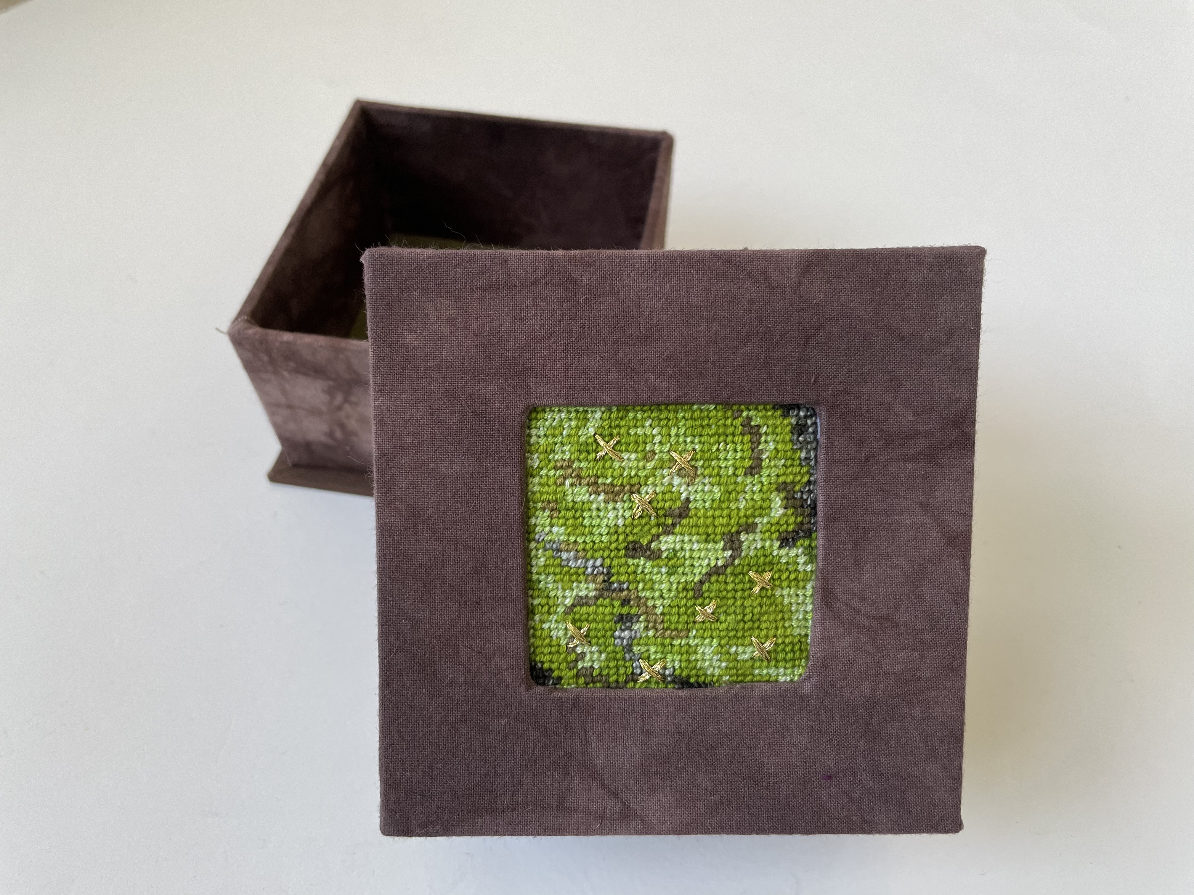 a box with an inset needlepoint of a moss with metallic gold Xs