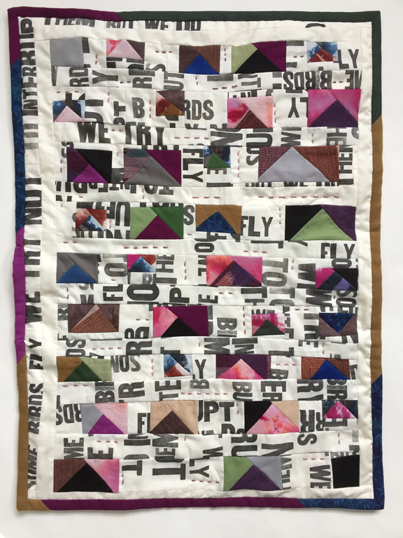 small scrap quilt with word fragments and variety of colored triangles that form flying geese pattern